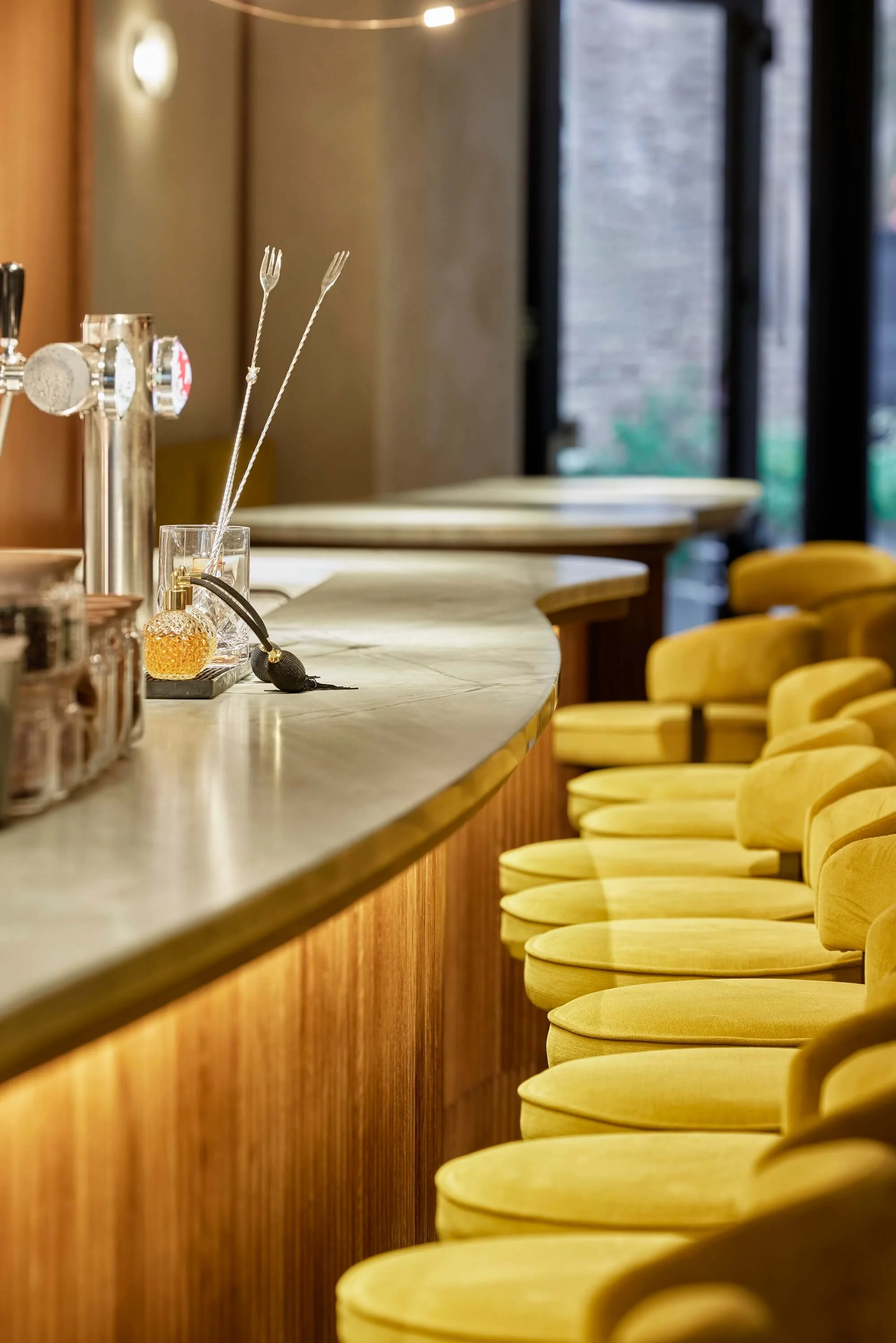 A detail shot of bar spoons, a bitters dropper and a jigger on the marble bar counter